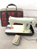 Full view of sewing machine seated in base with case lid and pedal