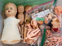 Overall lot showing multiple doll bodies, heads and limbs in bin and bags