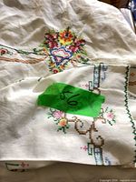 Folded embroidered cloth and napkin showing green tape number tag