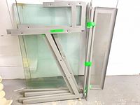Stacked glass panels and metal frame parts leaned against wall