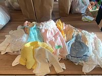 Pile of assorted pastel doll clothes on table