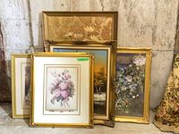 Group of five gold picture frames leaning against wall
