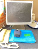 LG Flatron monitor, beige corded phone, closed blue device with camera case on top