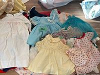 Overview of multiple doll dresses laid out on floor