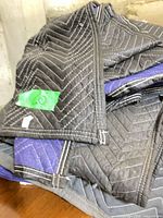 stack of dark grey quilted moving blankets with blue reverse