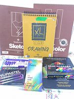 All art supplies grouped: three pads, coloured pencils tin, NuPastel box, Demco pastels box