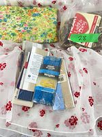 Group shot of fabrics, yarn in bag and stack of packaged sewing trims