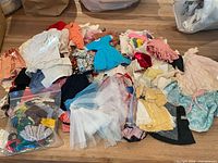 Overview of assorted doll garments spread out on table