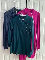 Three garments hanging: navy Lululemon, teal RolyPoly, fuchsia Dakini