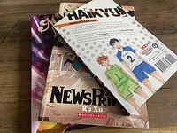 Stack of three graphic novels showing Haikyu!! back cover on top, NewsPrints middle, Nimona bottom