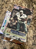 Stack of mixed football trading cards, top card Russell Maryland NFL Pro Set Dallas Cowboys, other cards partially visible beneath