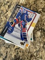 Stack of hockey trading cards showing an Upper Deck New York Rangers goalie card on top