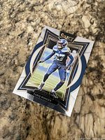 Front of Panini Select Tariq Woolen football card on granite surface