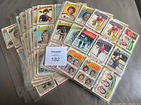 Stack of binder pages holding numerous 1976-77 O-Pee-Chee hockey cards with MaxSold lot tag visible