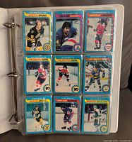 Nine player cards in binder page showing blue border 1979-80 OPC design