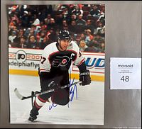 Full view of autographed 8 x 10 glossy color photo showing Eric Desjardins in Flyers uniform with blue Sharpie signature