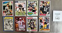 Eight football cards laid out in two rows on tabletop, plus lot number slip