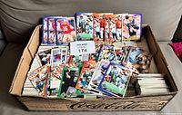 Open Coca-Cola tray filled with stacked football cards; several sample cards displayed on top along with lot number card