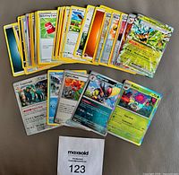 Fanned display of all 27 cards front side highlighting Ogepon EX, Kingambit, Infernape and other assorted cards