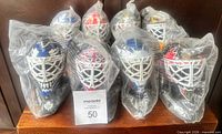Eight sealed miniature goalie masks grouped together on wooden shelf