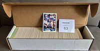 Open white cardboard set box containing full stack of baseball cards with one card displayed upright