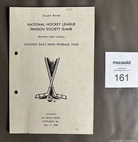 Front cover showing event title, crossed sticks graphic, location, date, two punched holes