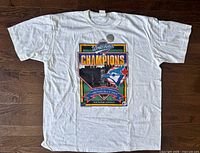 Front view of unworn Toronto Blue Jays 1992 Champions T-shirt showing graphic and hologram sticker