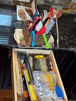Bin of utensils on countertop and open drawer showing BBQ accessories and cooking tools