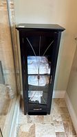 full view of black glass door cabinet beside shower