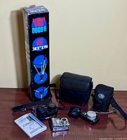 Group shot showing three cameras, Slik tripod box, two camera bags and charger