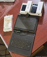 Lot grouping: two boxed iPhone 4S units, tablet in folio keyboard case, sealed USB cable