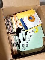 Open box showing two tightly packed rows of 45 rpm records in sleeves