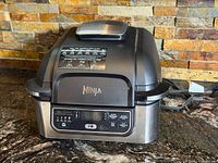 Front view of Ninja Foodi indoor grill showing hood, control panel, and exterior condition