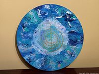Front view of circular acrylic painting showing abstract design and gold symbol