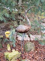 Full view of metal heron sculpture standing in garden setting
