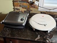 Breville stainless-steel grill and Hamilton Beach white grill side by side on countertop