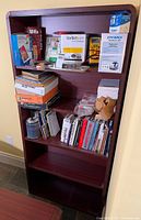 Front view showing entire tall dark wood bookcase with five shelves