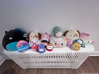 Full lineup of all Squishmallows on white bench