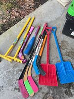 All items laid out: hockey sticks, rakes, shovels, foam bat