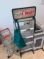 Overall view of Fresh Mart rack with apron and shopping cart