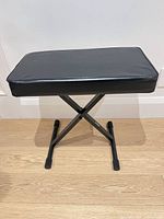 Overall view of black vinyl padded keyboard bench on X-style metal frame