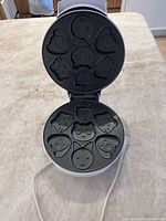 Waffle maker open showing nine animal-shape molds