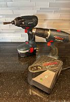 Impact driver with battery, drill, and charger on countertop