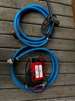 Pump, hoses, nozzle, power leads displayed on wooden surface