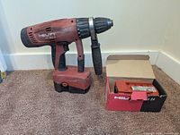 Drill with installed battery, side handle, boxed spare battery