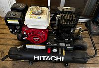 Overall view of Hitachi twin-tank gas air compressor showing Honda engine, twin tanks, control panel and branding