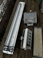 Four assorted light fixtures laid out on wooden deck