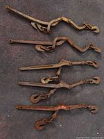 Five rusted lever load binders on ground