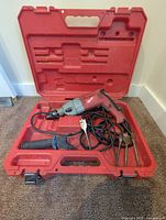 Drill, handle, bits, cord inside open red case