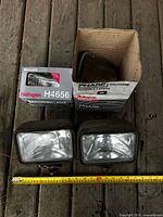 Overall lot showing two boxed sealed beams and two driving lights with measuring tape